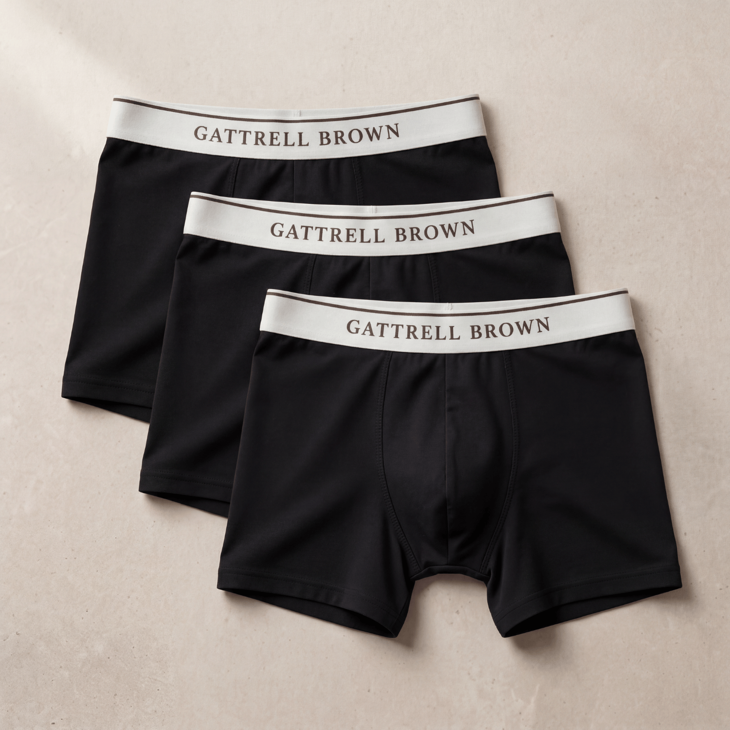 Three black boxer briefs with white waistbands labeled 'Gattrell Brown' on a beige background.