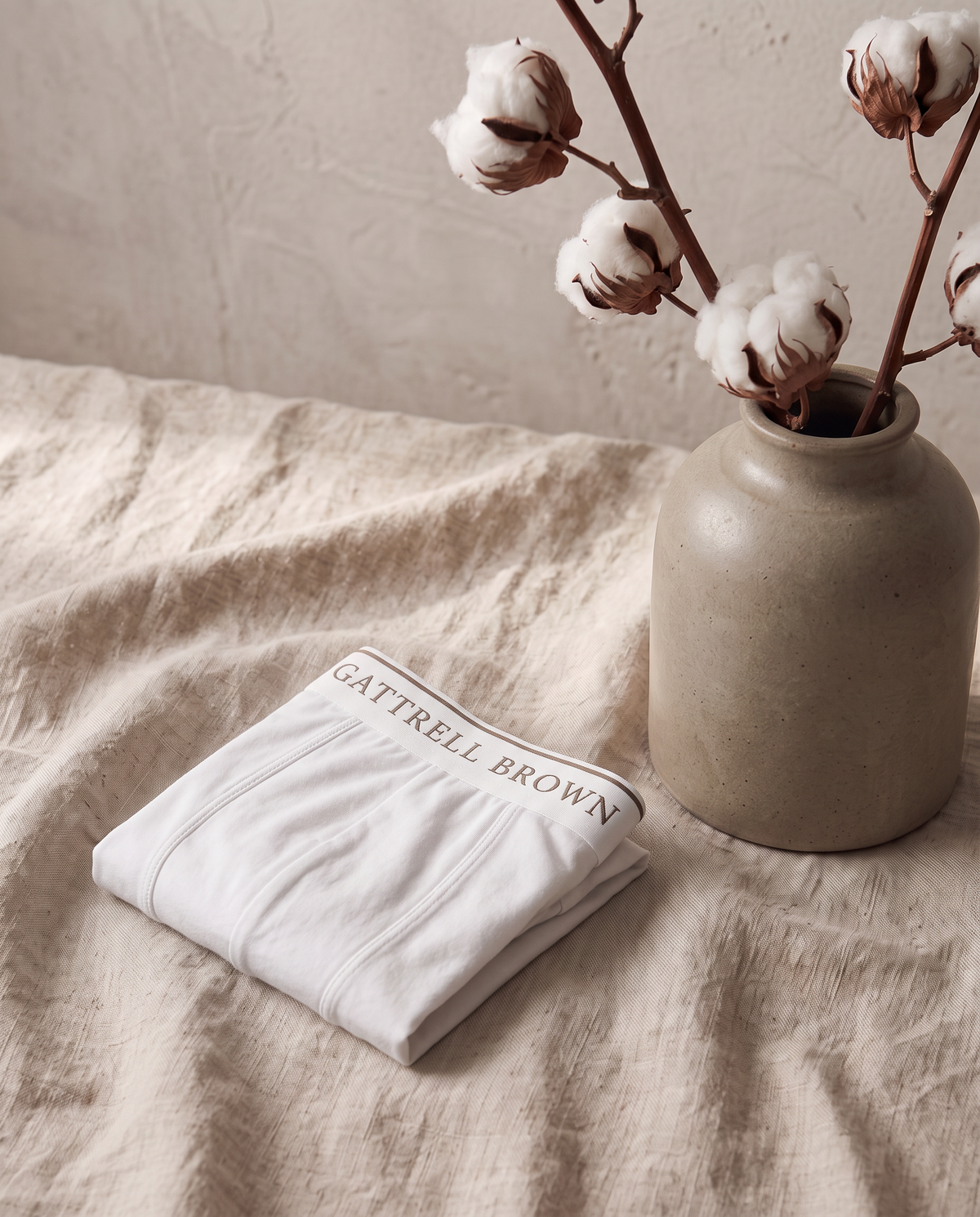 White Original Trunk folded on linen beside a vase of raw cotton